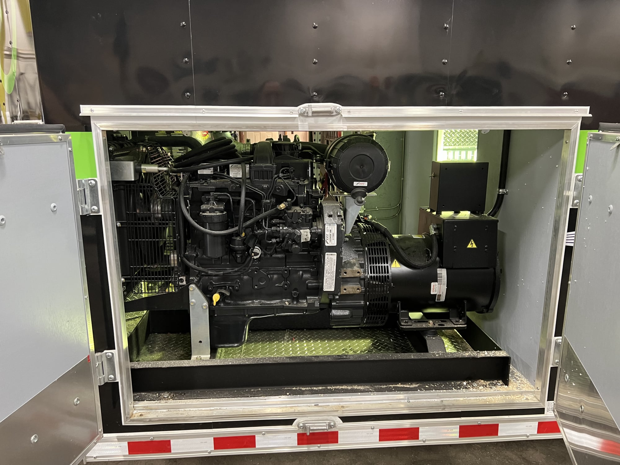 Open generator compartment on a trailer, diesel engine, Fleetguard filter and diamond-plate floor.