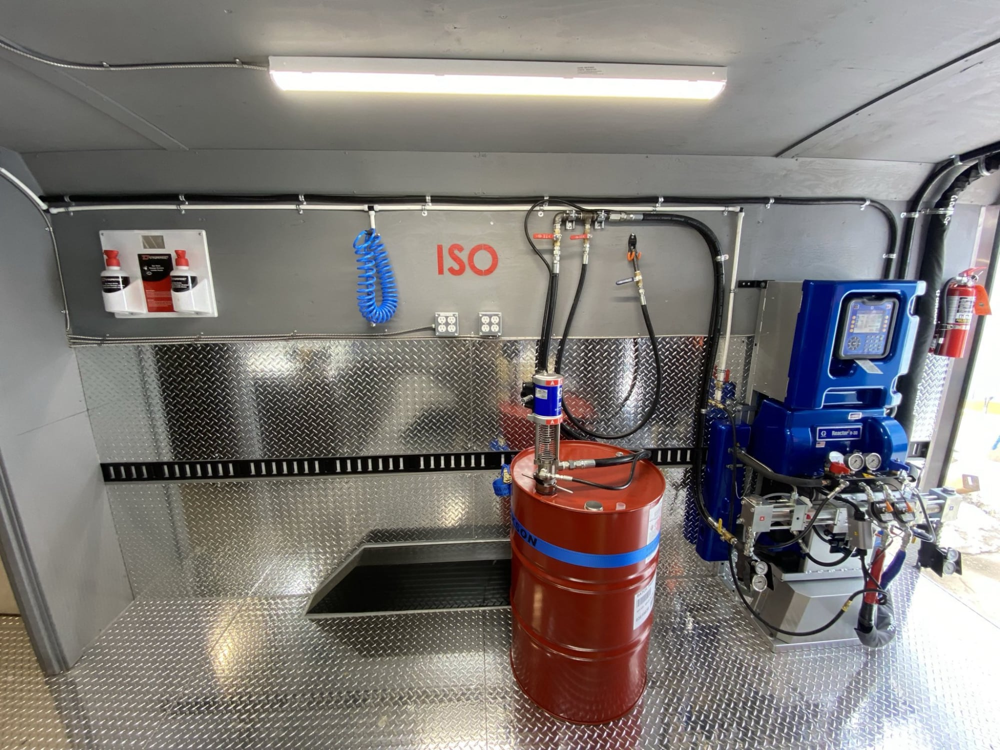 Graco Reactor and red ISO drum inside a finished spray foam rig.