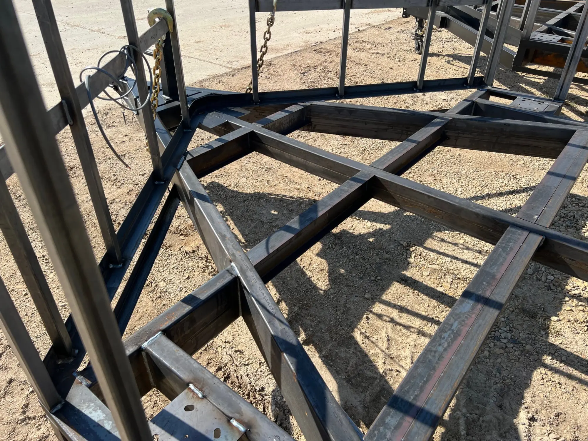 Steel trailer frame under construction in the yard.